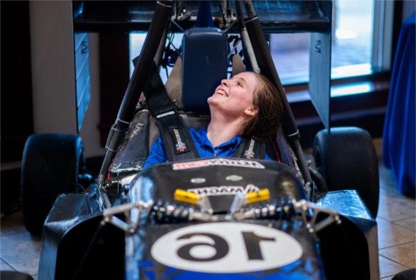 Annika Mattson, with the GVSU Formula SAE racing team,  sits in the car while presenting during the 2024 Reach Higher Showcase.