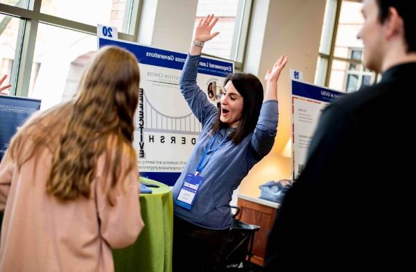 艾比·萨克斯(Abby Sachs)是Peter C .的项目经理. 库克领导学院， 4月21日，一名学生在Reach Higher Showcase展位旋转游戏轮，她举起双臂庆祝.