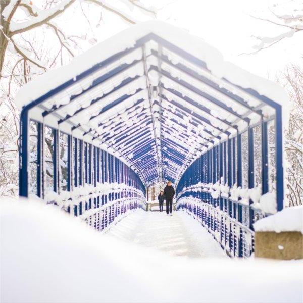 Students walk over the blue Little Mac Bridge surrounded by the results of a recent snowfall.